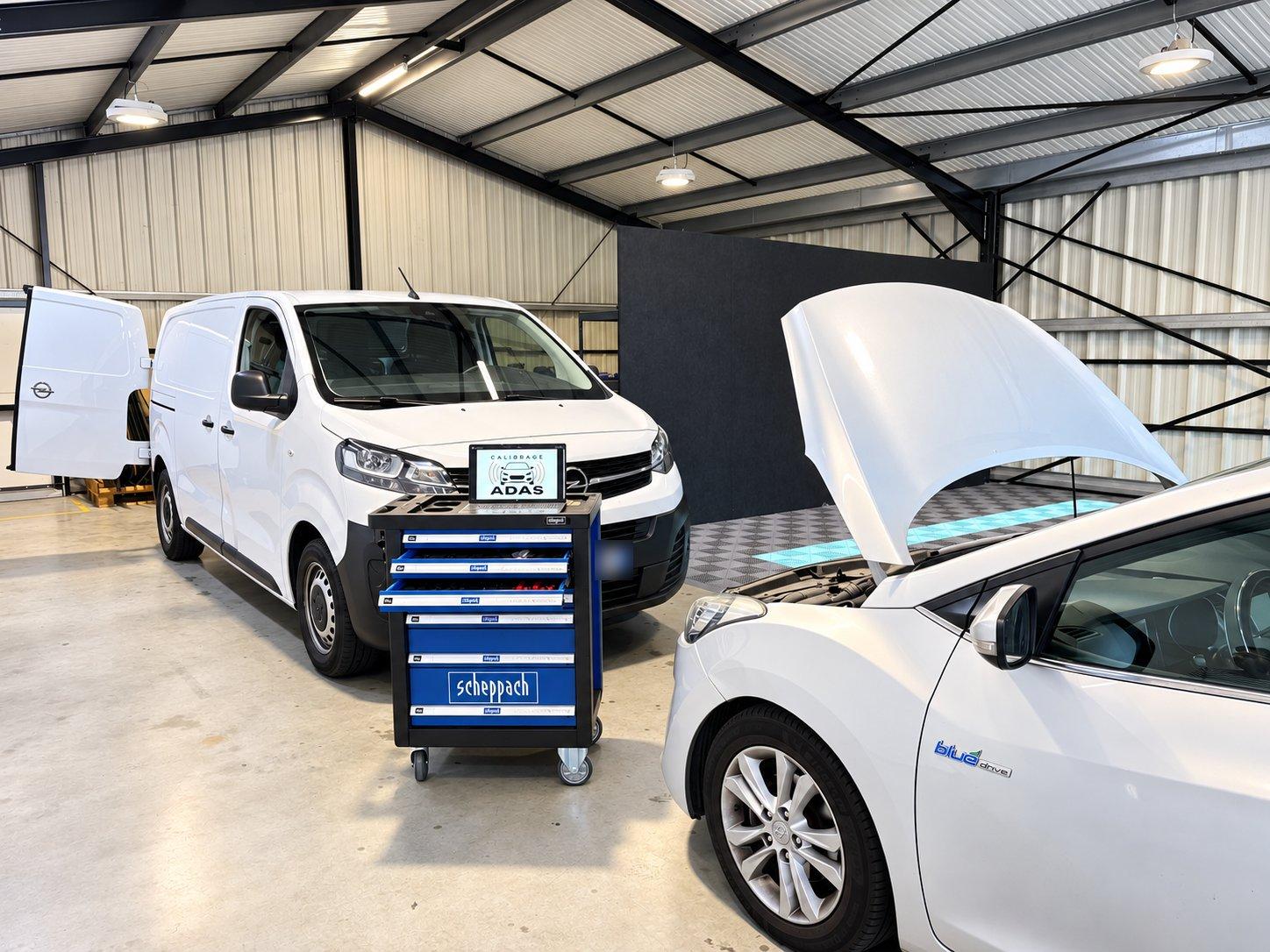 Atelier de calibrage : une servante d'outillage équipée d'une tablette ADAS Calibrage entre un utilitaire et une voiture capot ouvert.