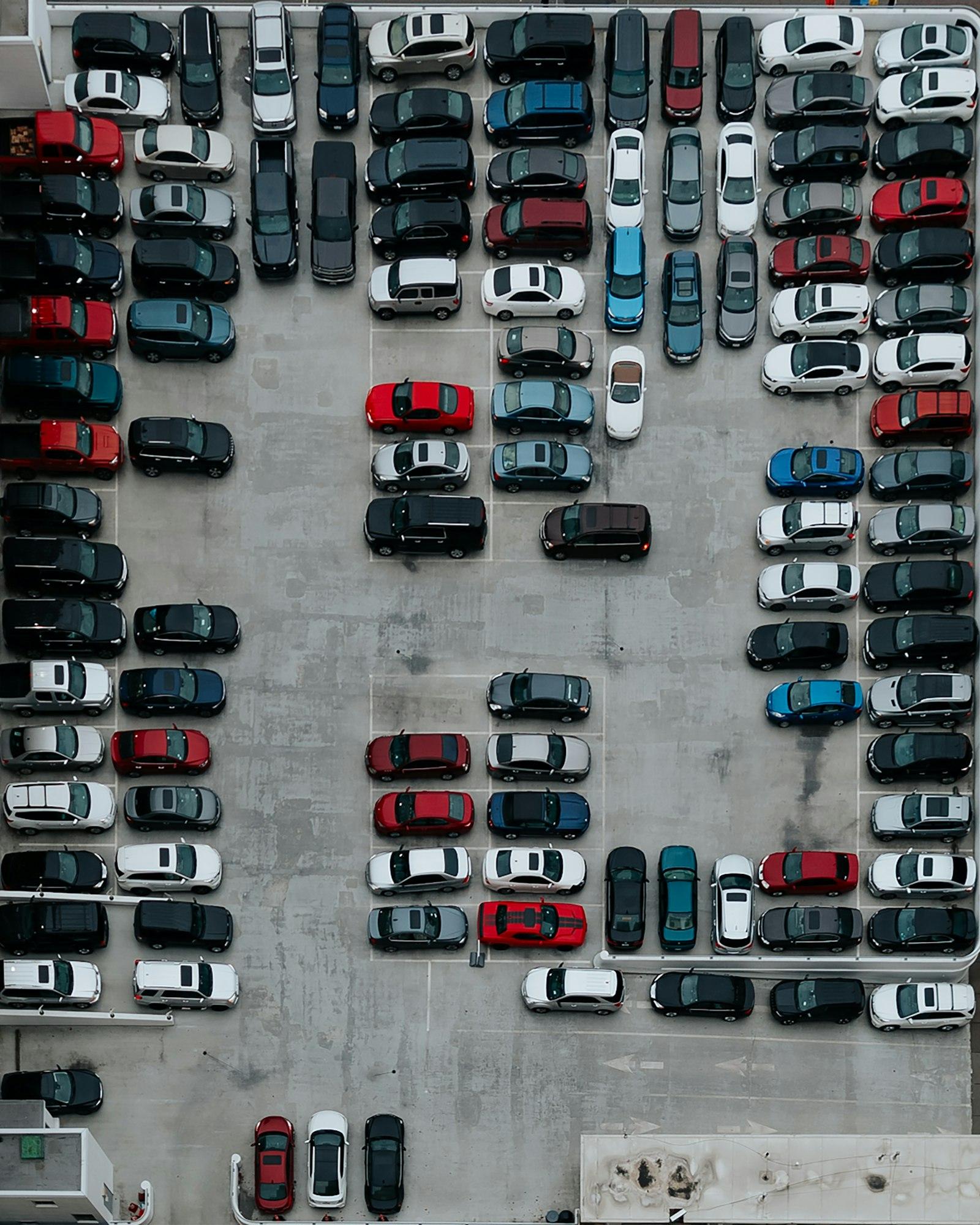Vue aérienne d'un parking rempli de véhicules alignés.